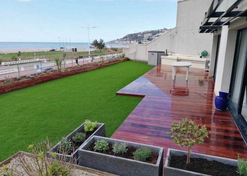 Conception et pose d’une terrasse bois exotique sur plots avec gazon synthétique et plantations maritimes à Montivilliers près du Havre