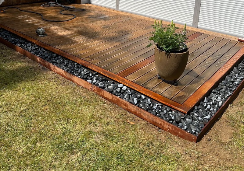 Pose de terrasse en bois pin classe 4 au Havre avec aménagement de galets noirs ébano pour un extérieur design et naturel